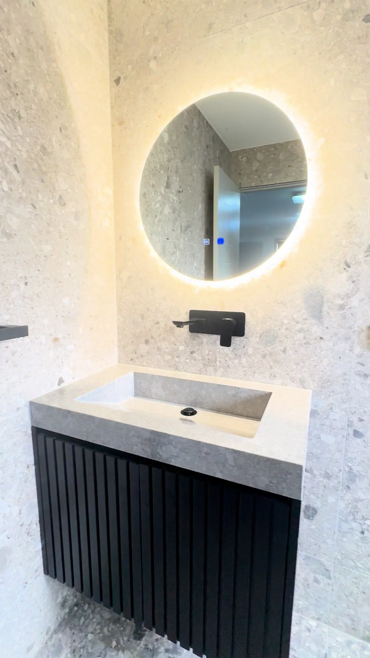 Denham Court bathroom with illuminated round mirror, integrated basin and fluted dark vanity
