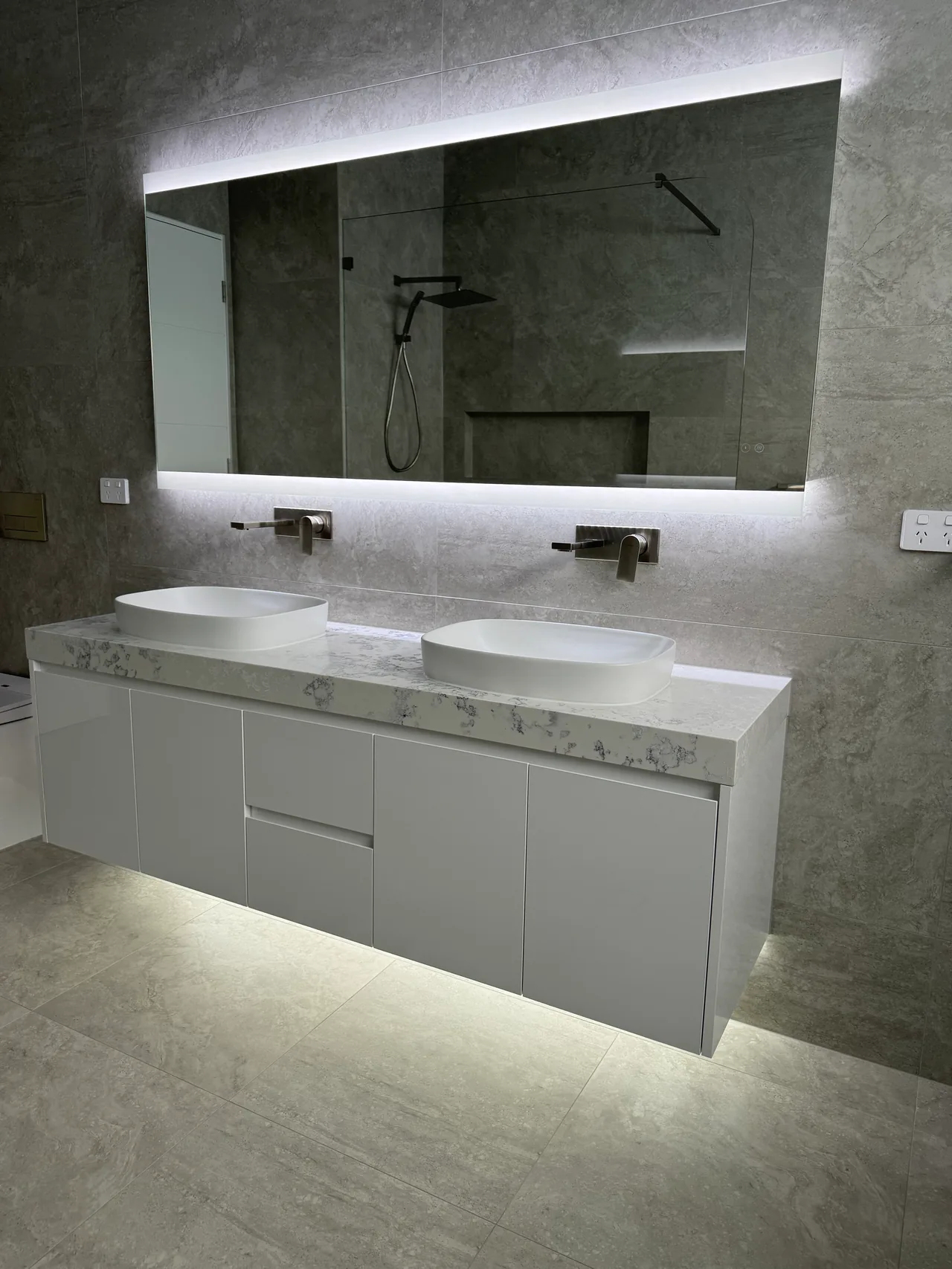 Edensor Park bathroom with a floating double vanity, white basins, illuminated mirror and under-cabinet lighting