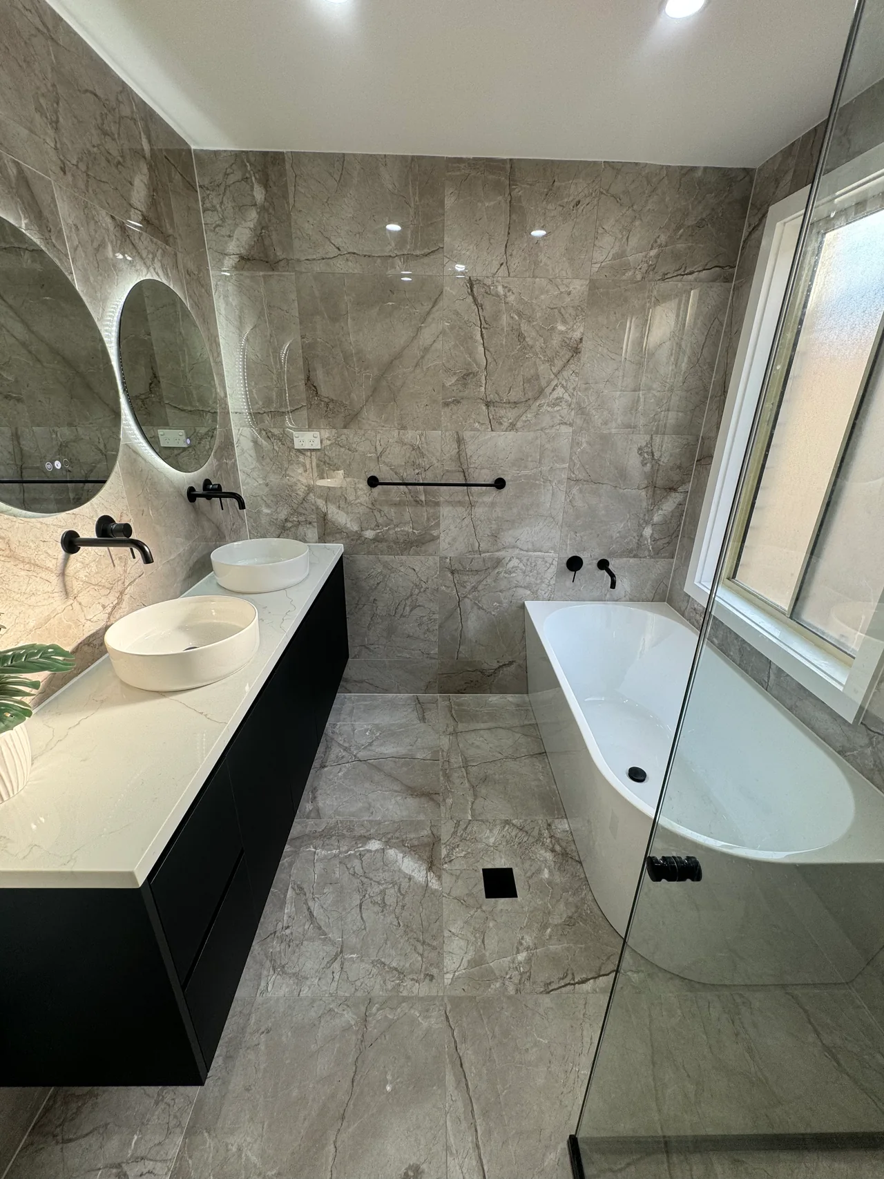 Prestons Bathroom 1 after renovation with twin illuminated mirrors, black double vanity and freestanding bath